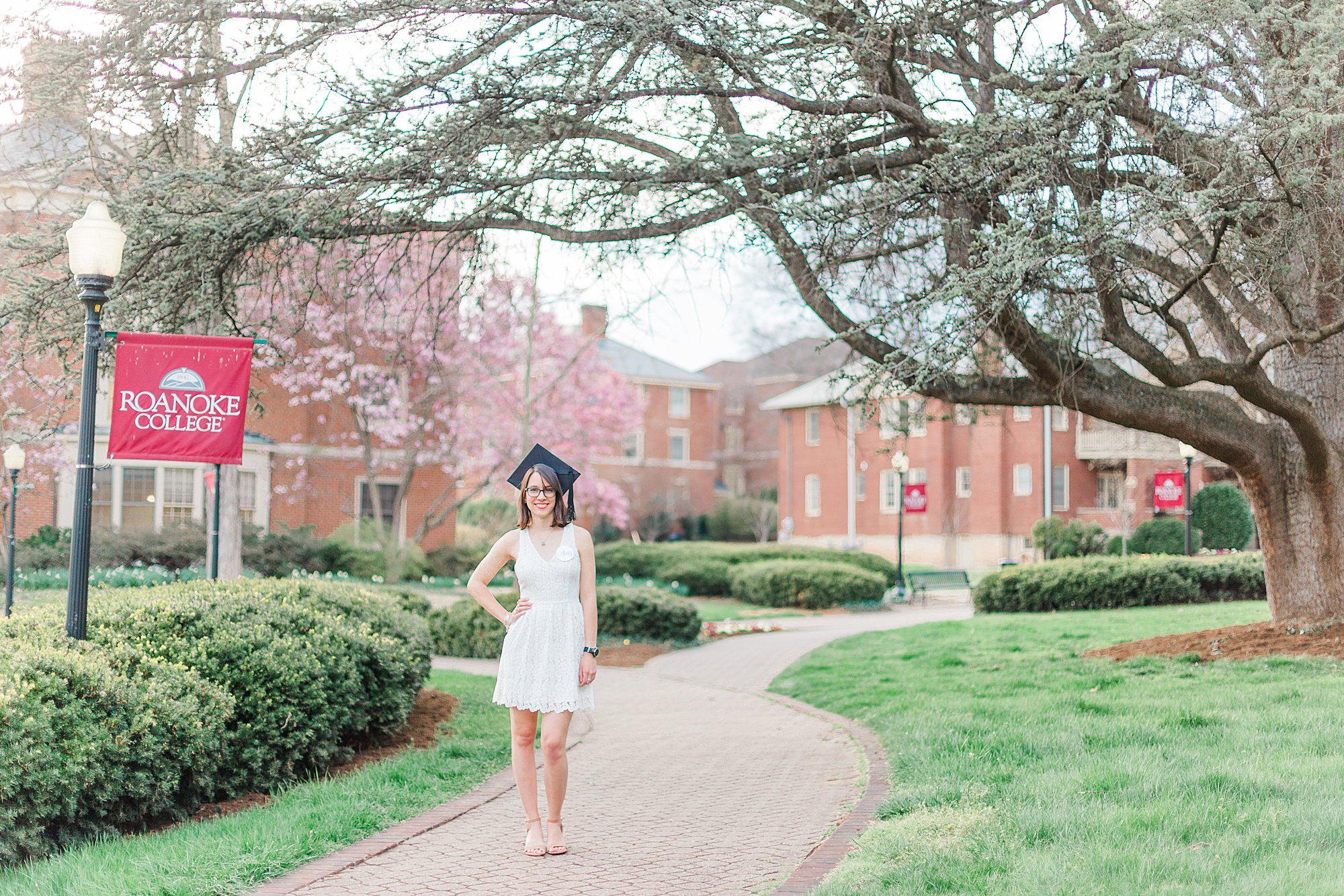 Roanoke College graduate smiles under tree.