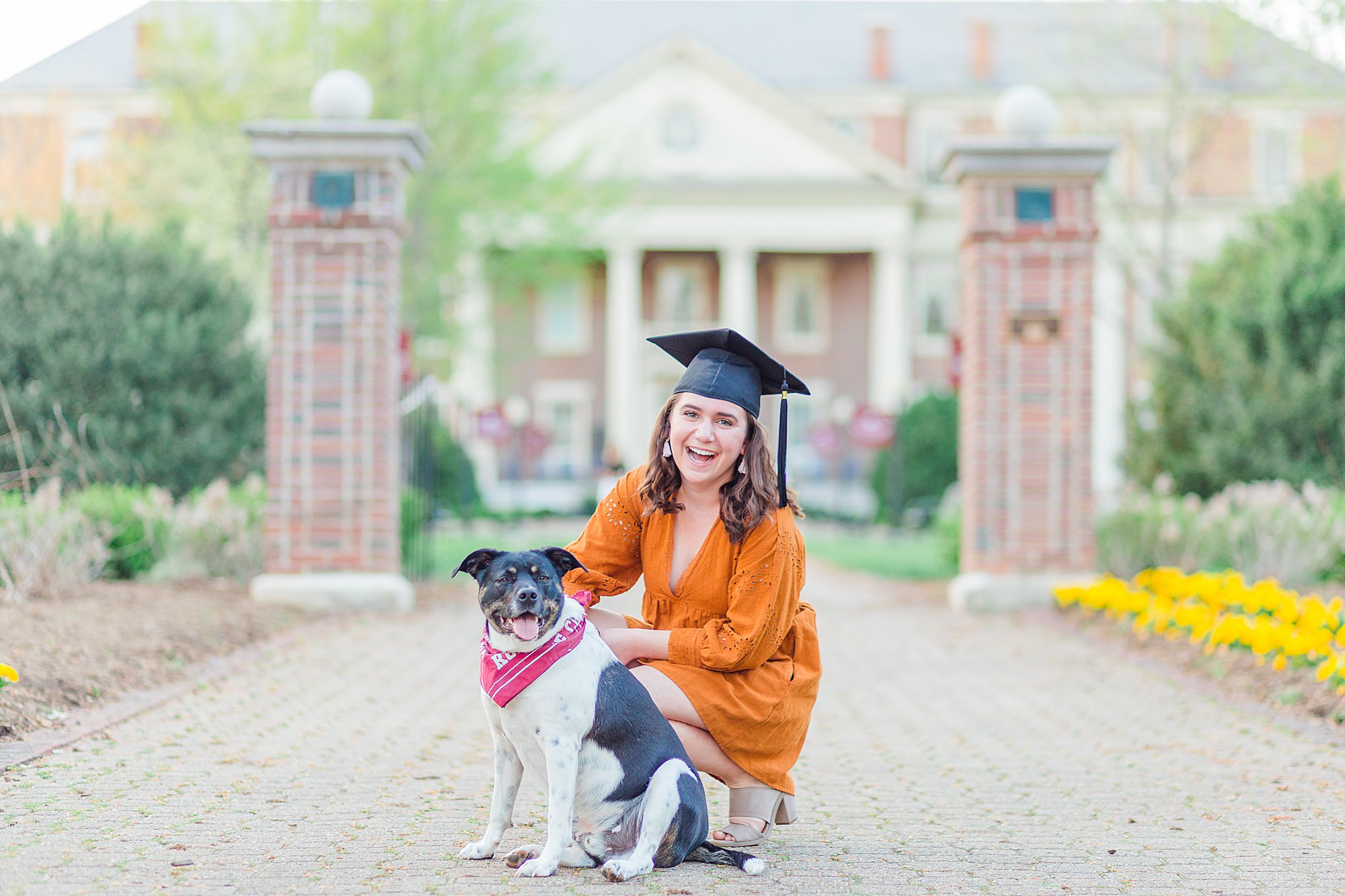 Girl posing with dog for graduation picture.