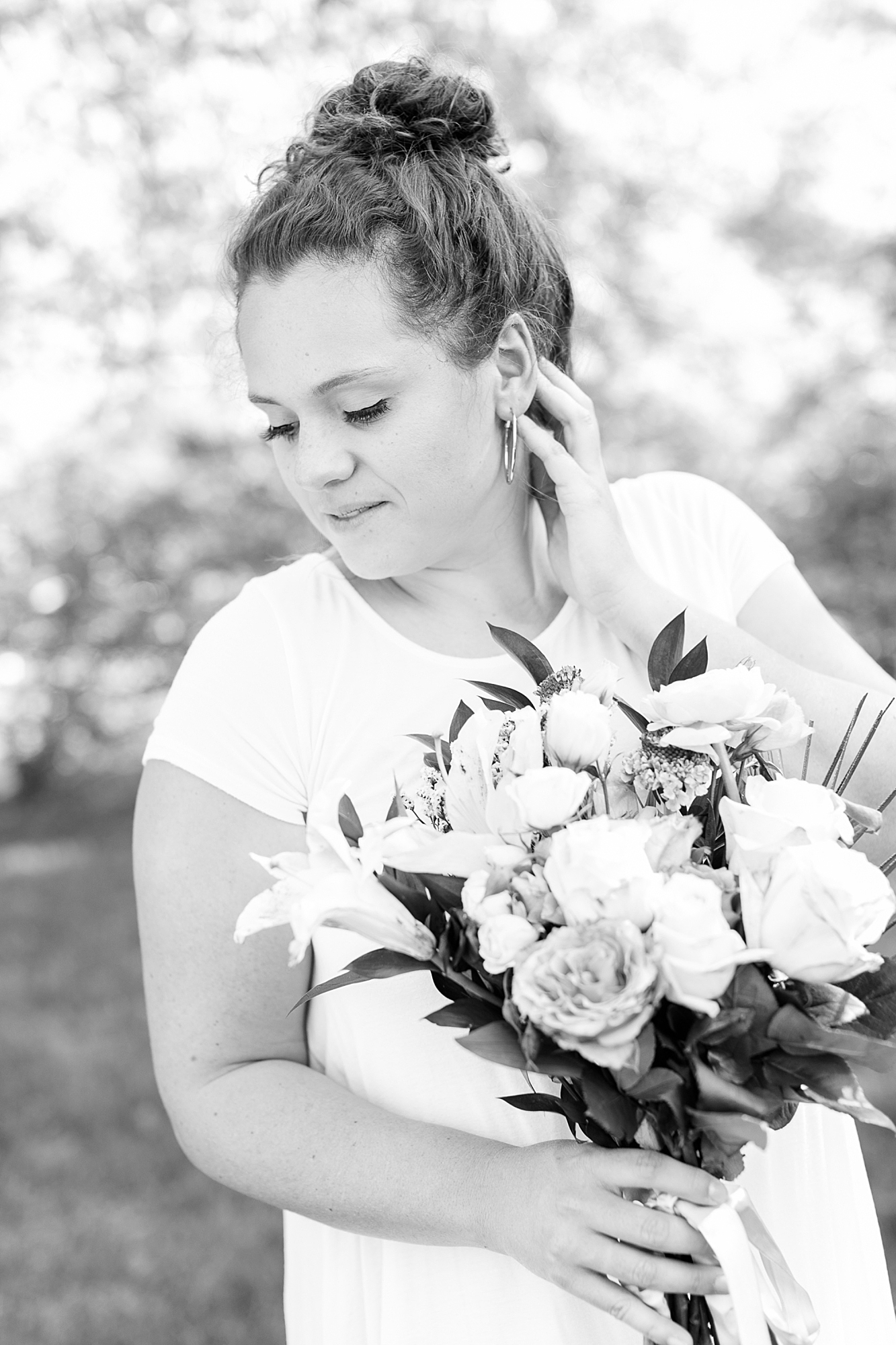 Black and white photo of Ashley Eagleson posing with flowers. 