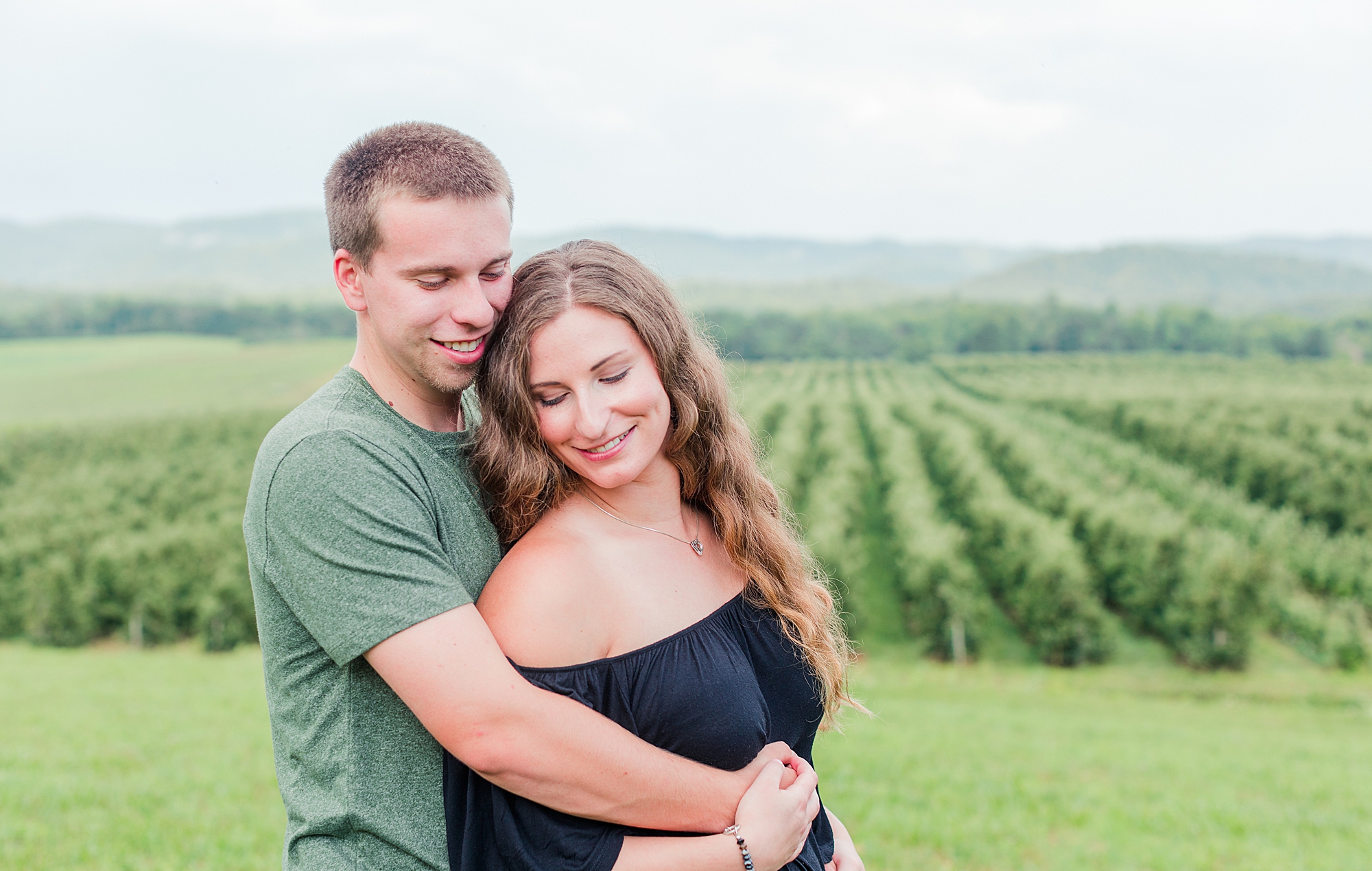 Couple hugging during engagement session at vineyard.