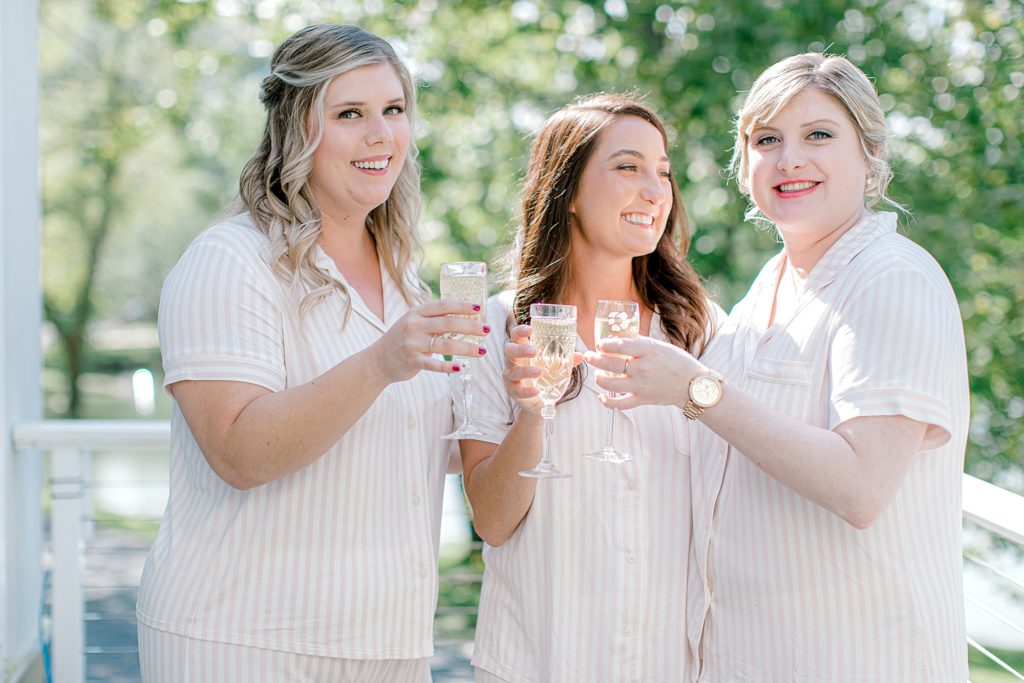 Bride and bridesmaid cheering with champagne in getting ready outfit.