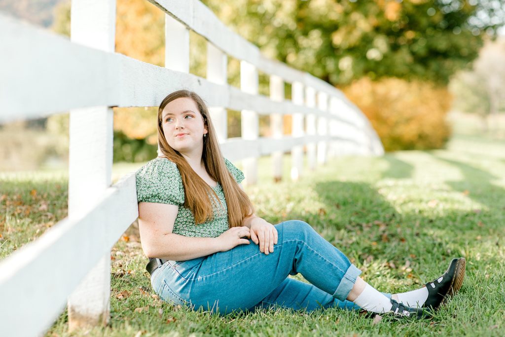 Senior sitting down by fence for senior session at Castle Hill.