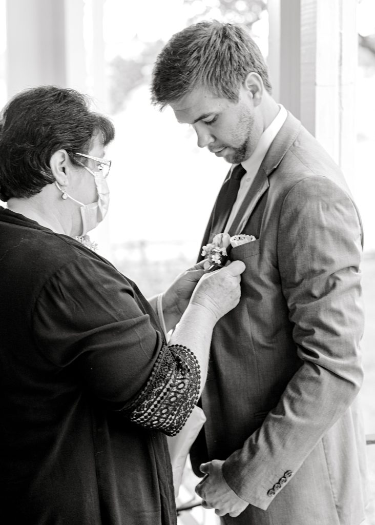 Grooms mother helping pin boutonnière. 