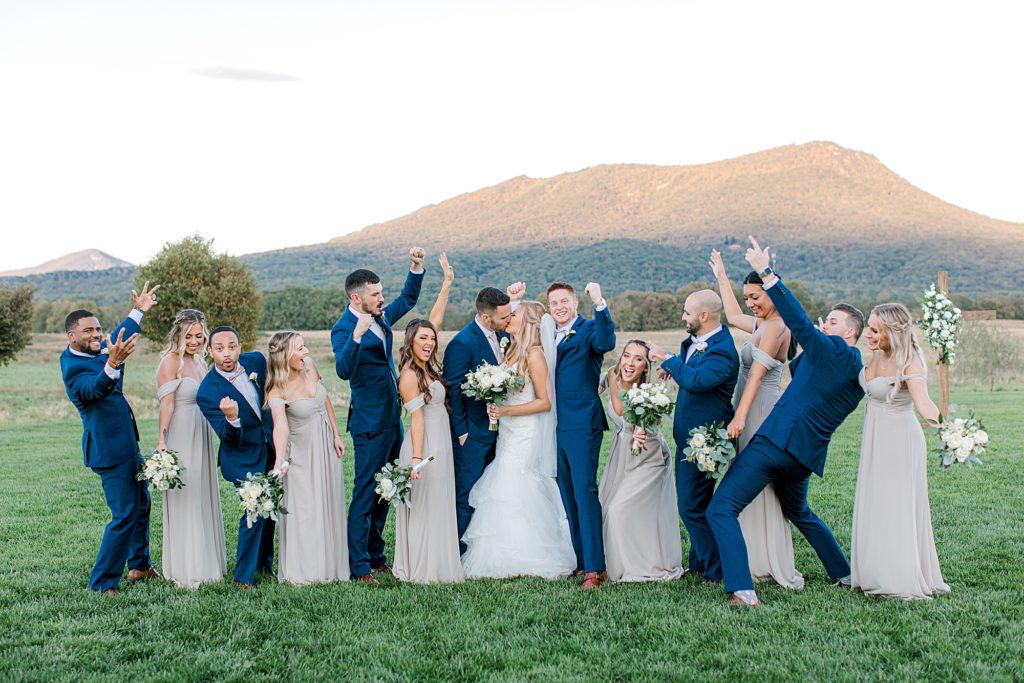Fun Wedding party photo. Bridal parting cheering while bride and groom kiss.