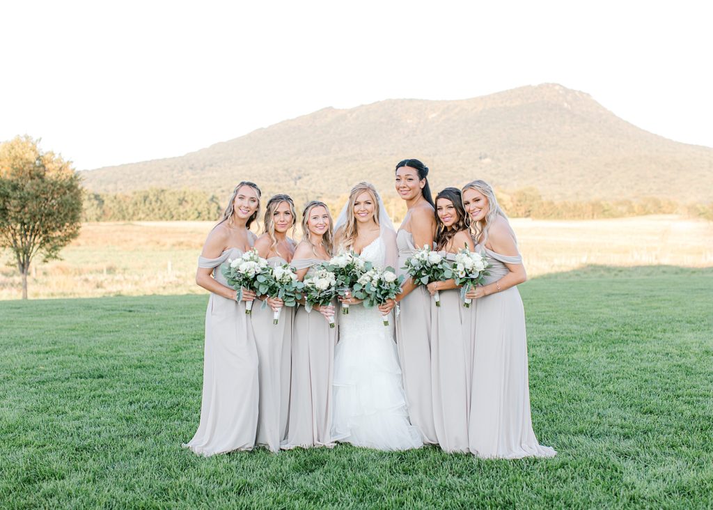 Bride and bridesmaid smiling at camera for group photo with mountain in background