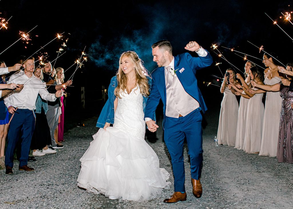 Bride and groom cheering walking through sparkler exit.