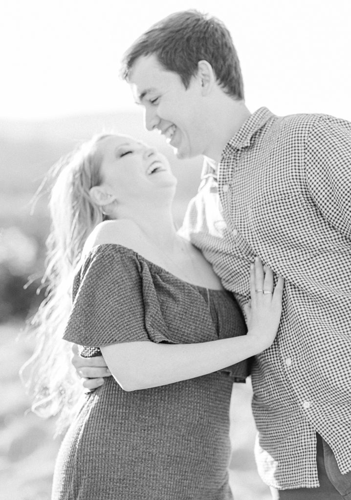 Black and white candid engagement photo image in field during golden hour.