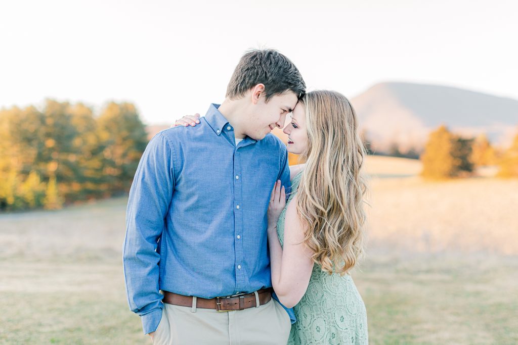 Boy wearing blue collard shirt and girl wearing green dress posing for engagement photos at wedding venue in Lexington, VA.