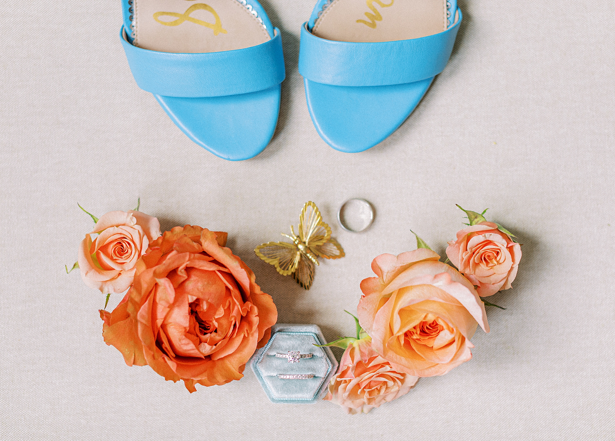 Flatlay bridal details with blue shoes and golden butterfly pin for wedding at The Market at Grelen..