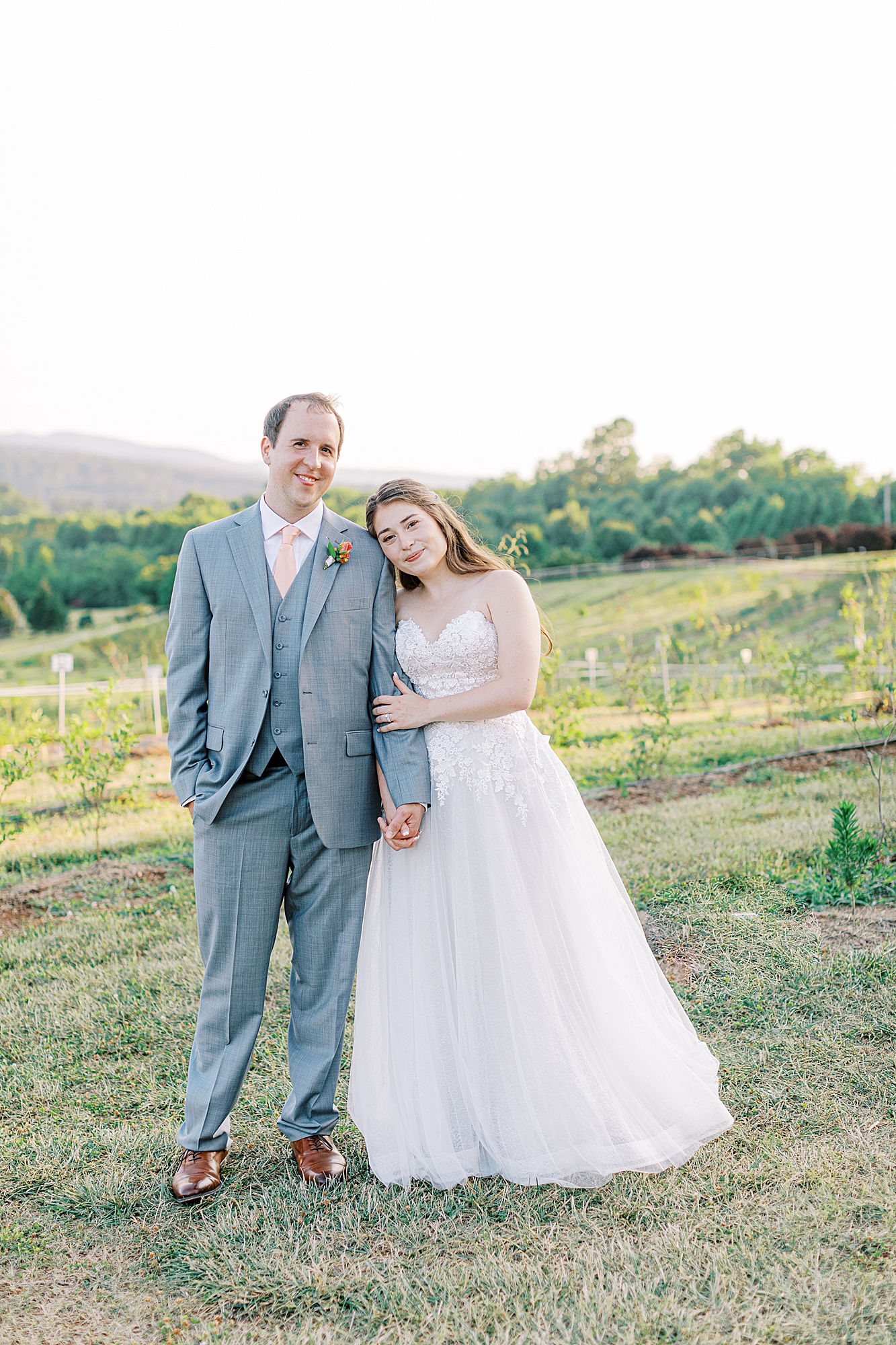 Bride holding onto grooms arm smiling at the camera during sunset portraits taken by Ashley Eagleson Photography.
