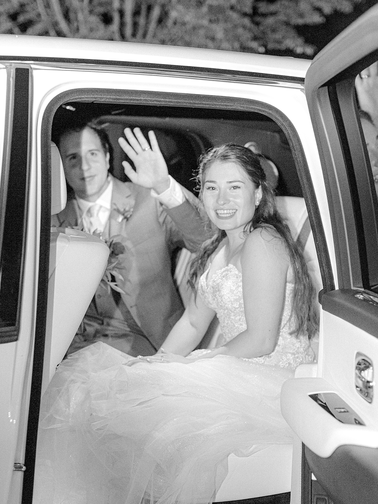Bride and groom in Dream Works Motorsports car waving goodbye at end of wedding.