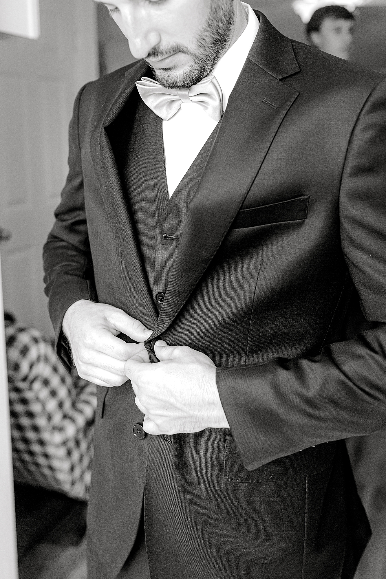 Groom buttoning tux for wedding.