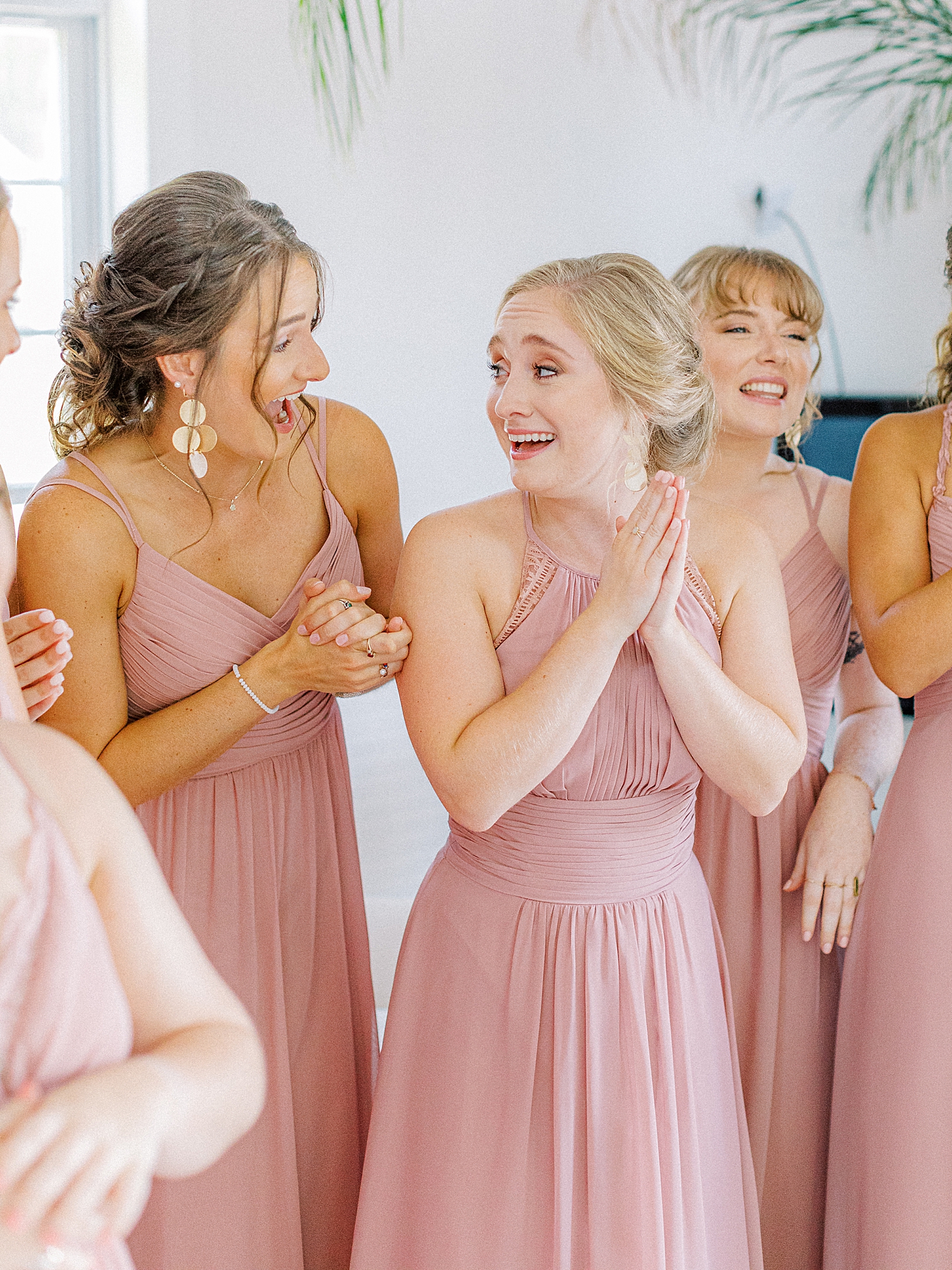 Bridesmaid wearing blush dresses clapping for bride.