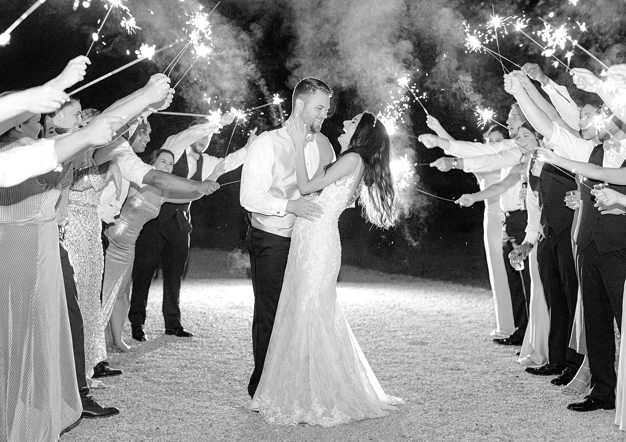 Bride and groom joyfully laughing under sparklers.