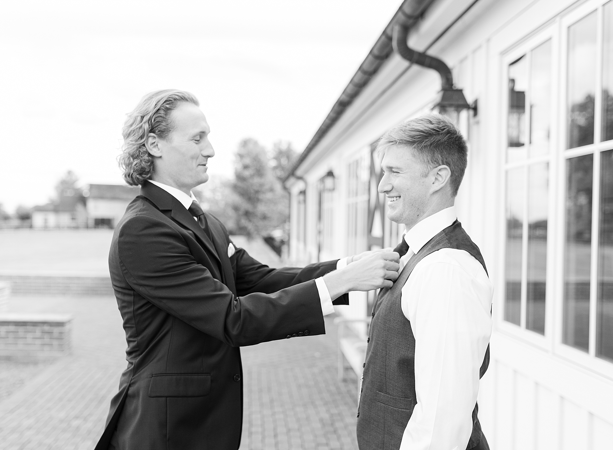 Best man helping groom tie the tie.