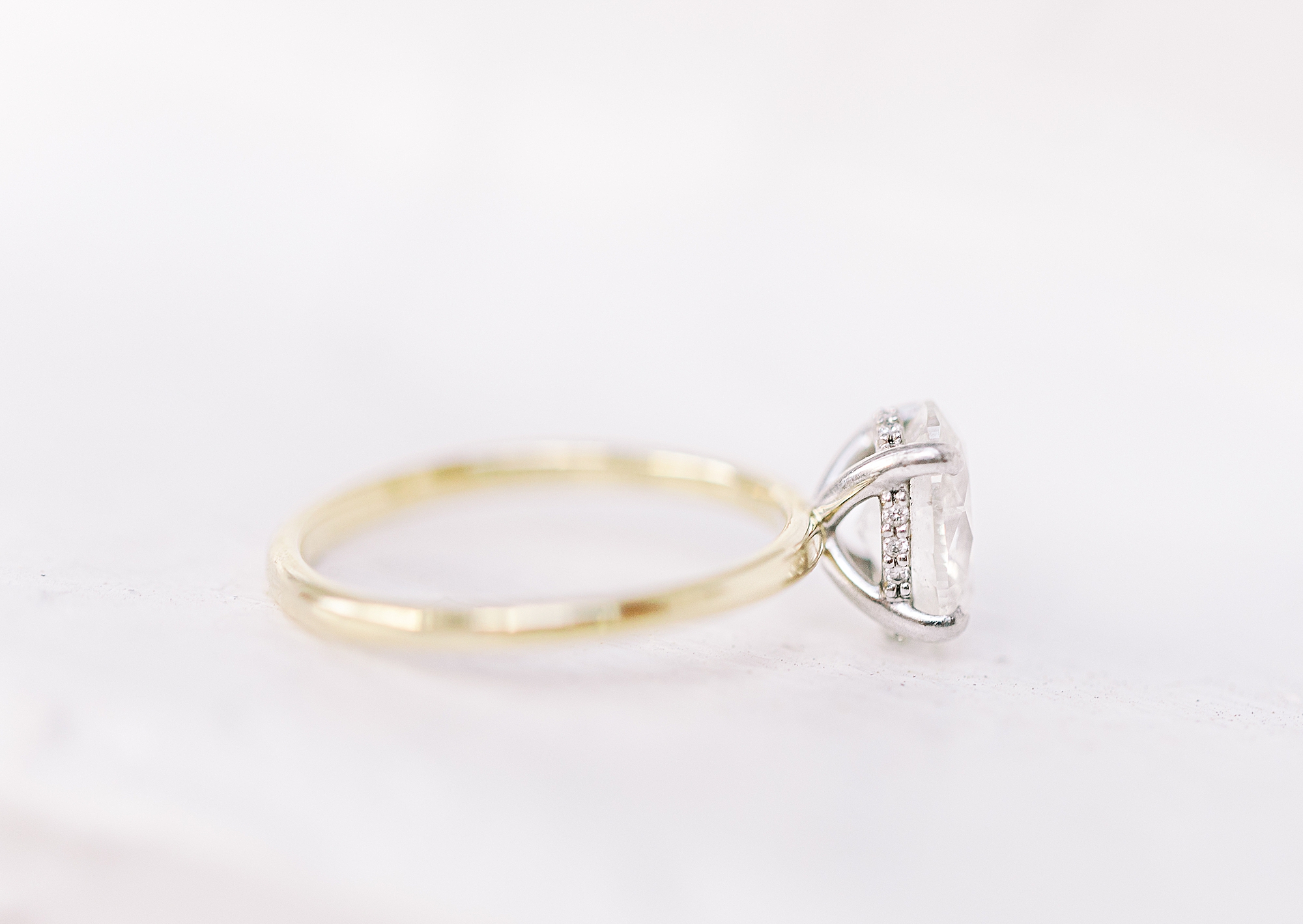 Side view of oval diamond engagement ring with thin band.