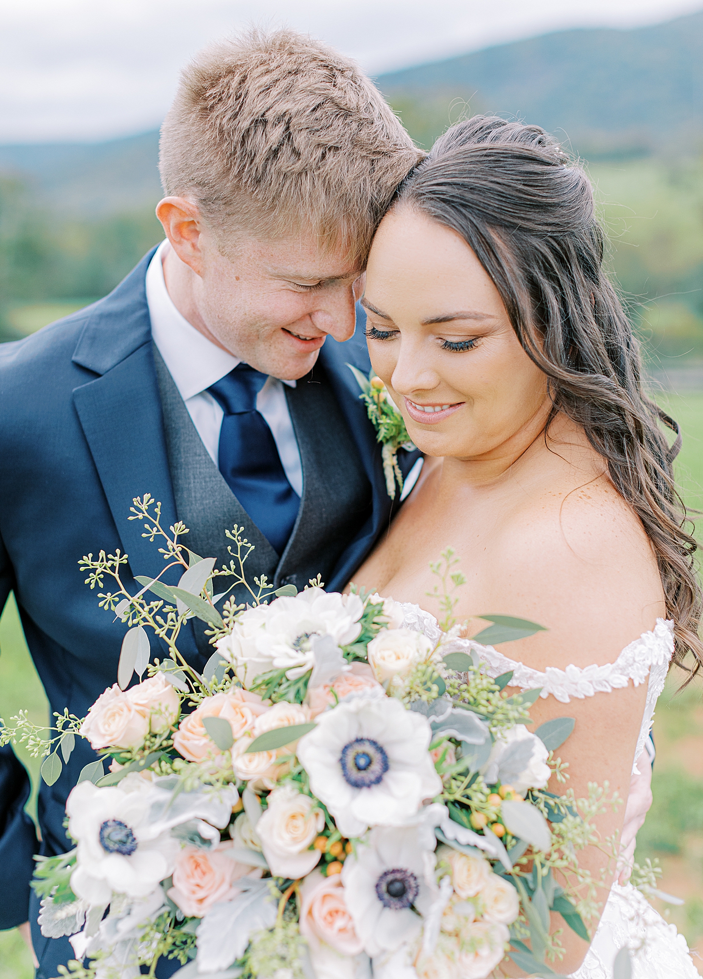 Portrait of bride holding blush and blue bouquet with groom. 