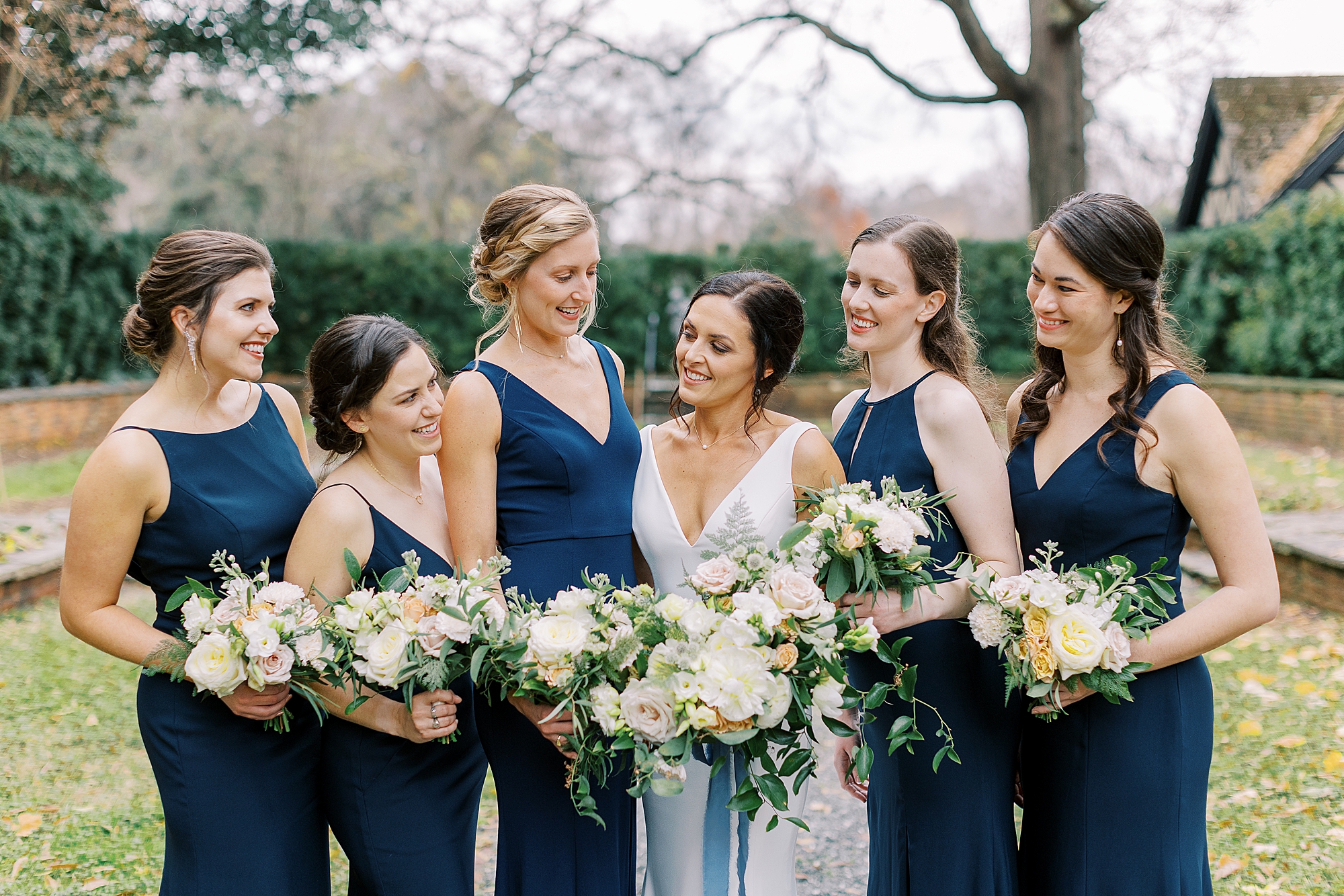 Bridesmaid wearing navy blue laughing with bride at winter wedding by Agecroft Hall.