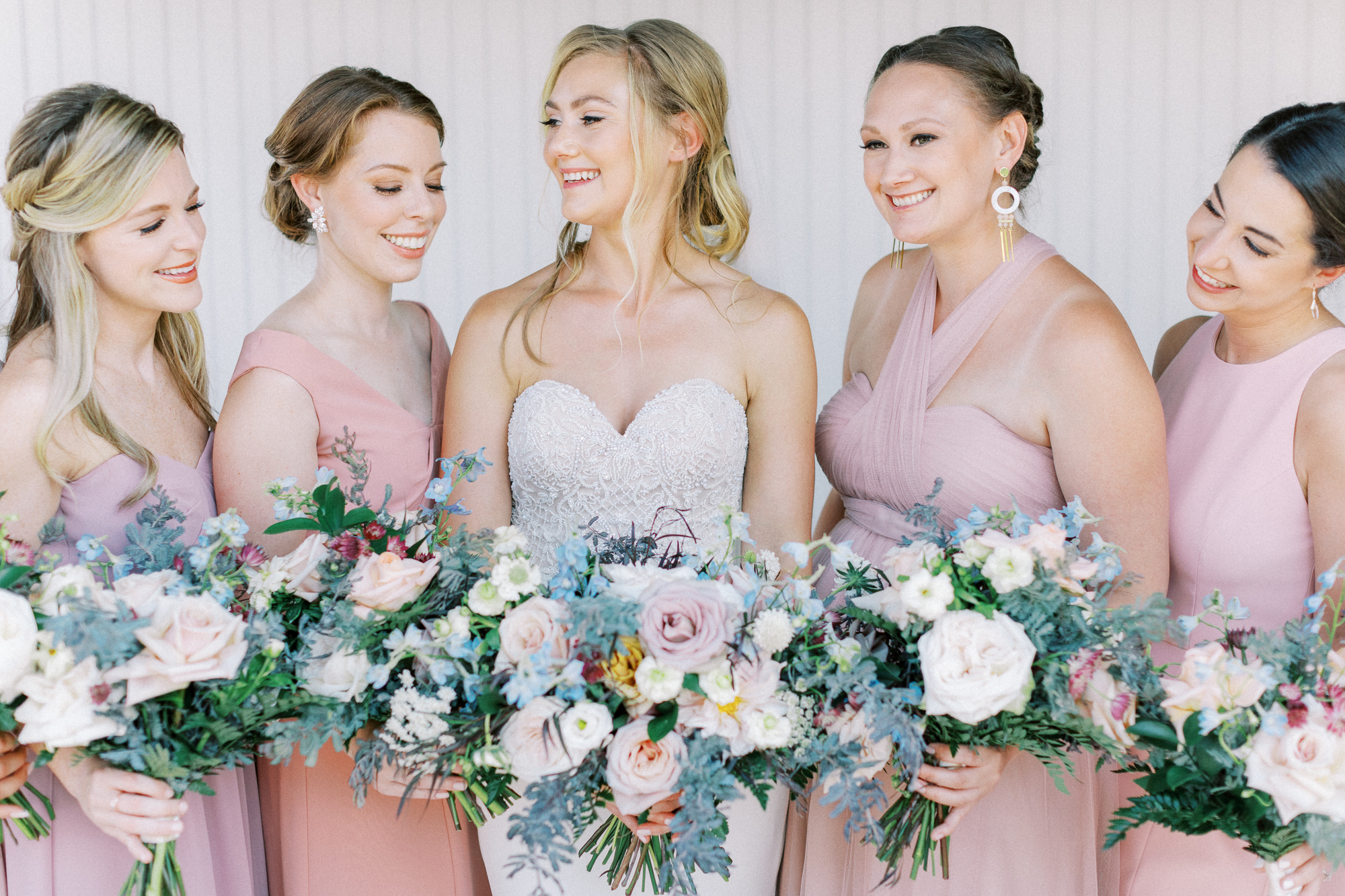 Bridesmaids in blush pink dresses with bride holding Spring bouquet for wedding at Chesapeake Bay Beach Club.