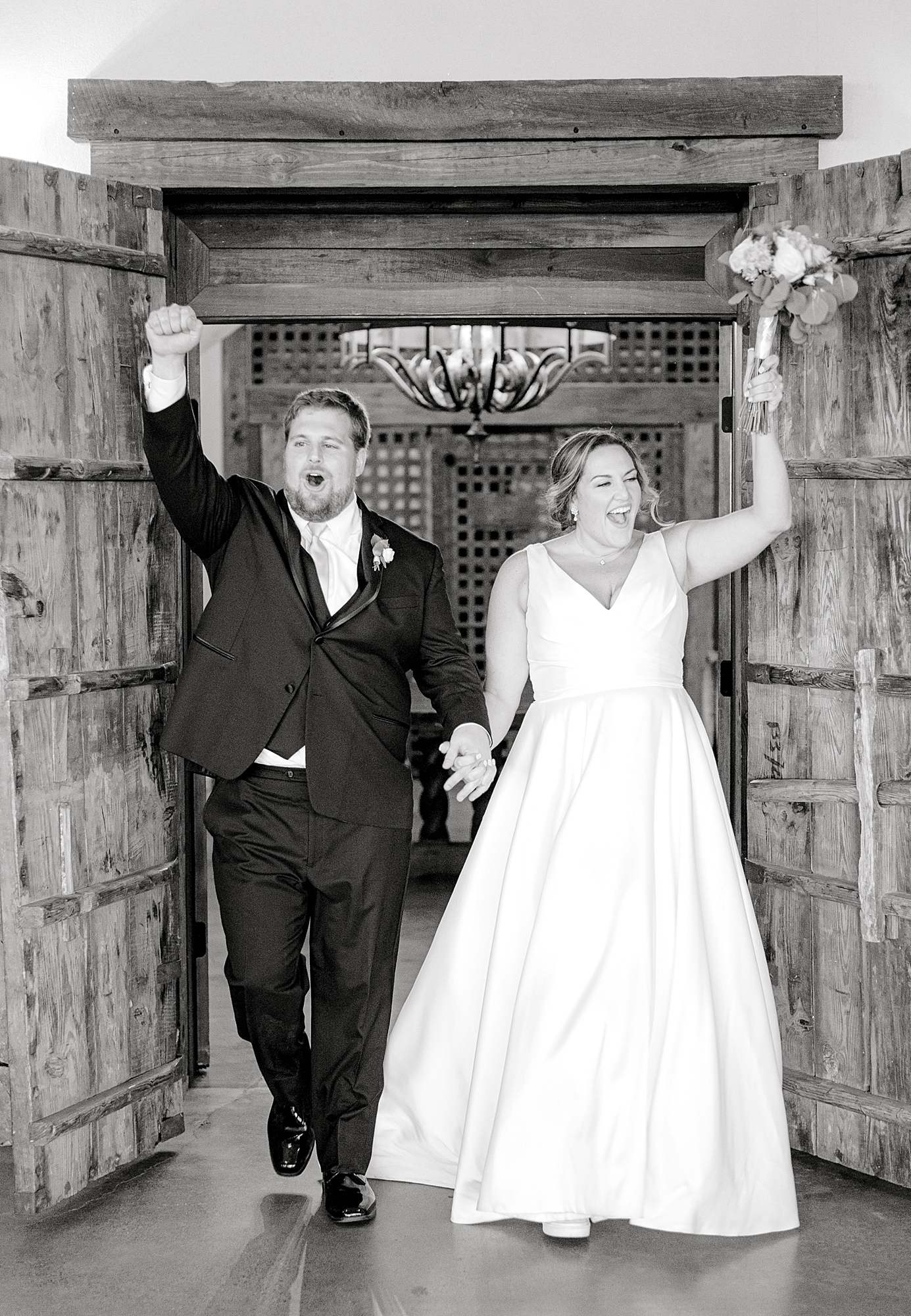 Bride and groom entering into reception with arms raised.