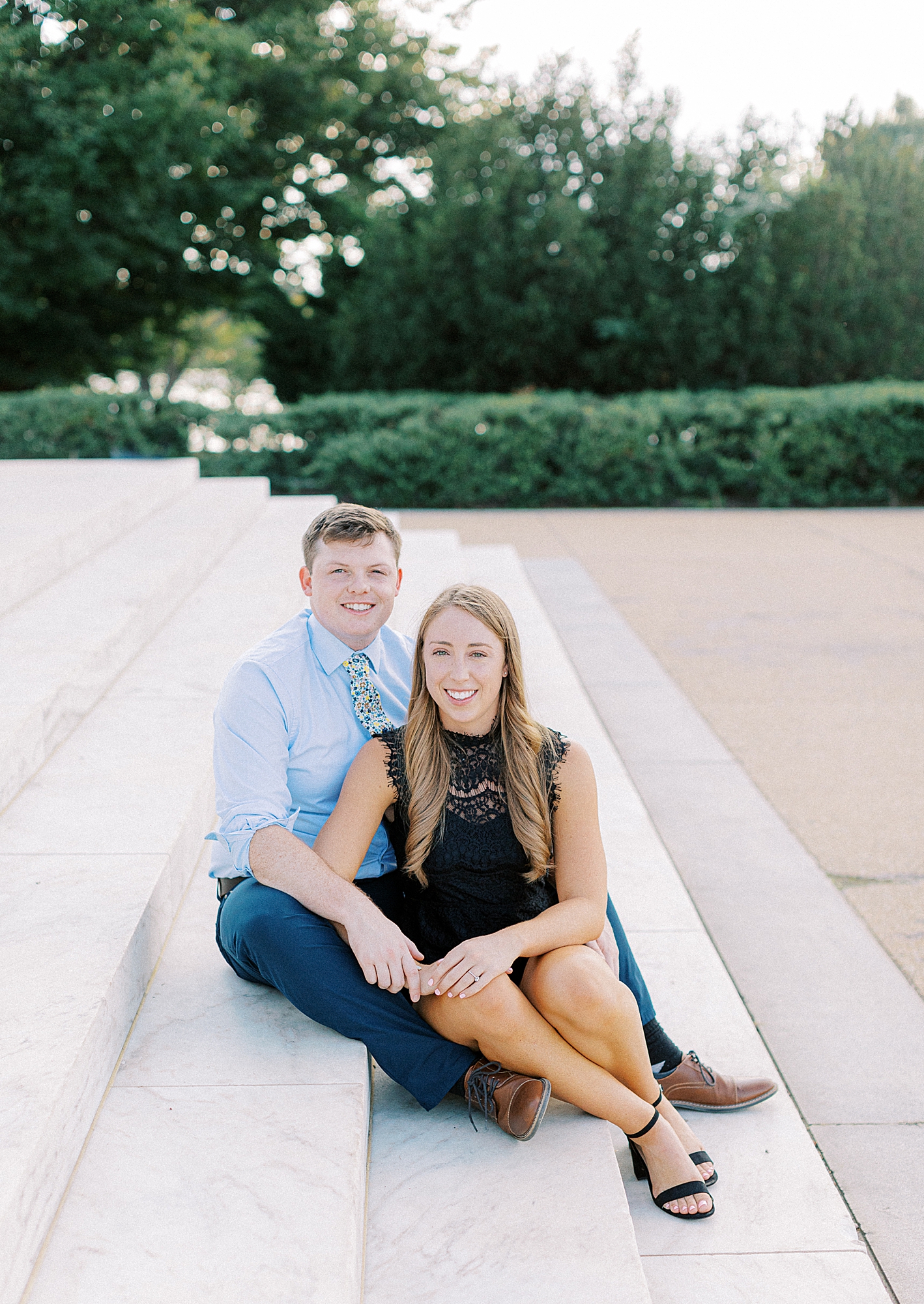 Couple sitting on the steps at Jefferson Memorial smiling at camera.
