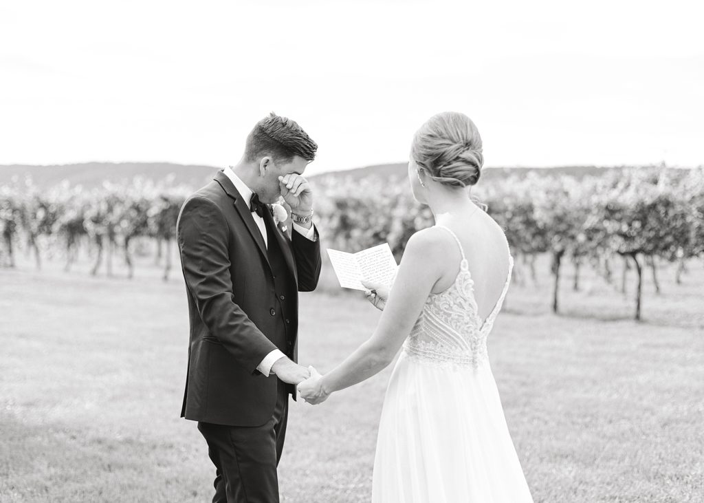 In the vineyards at Keswick Winery, groom wipes away tear while reading vows.
