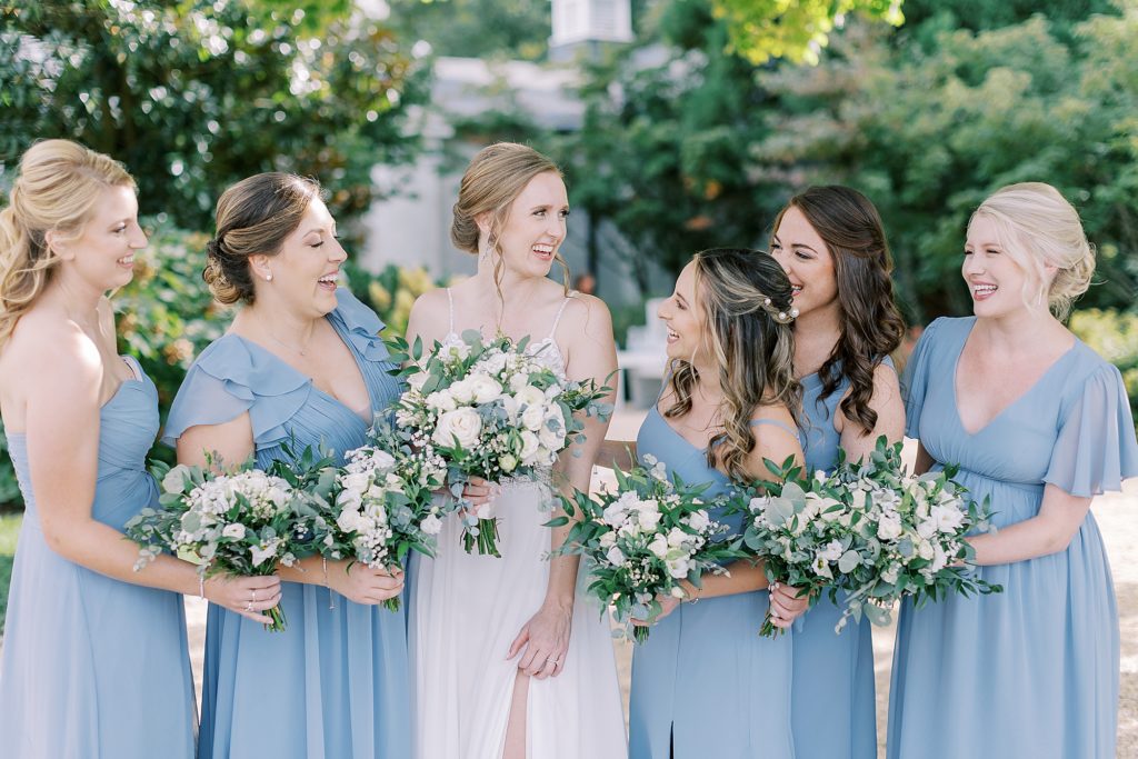 Bridesmaids wearing blue dresses from Azazie holding bouquets made from Colonial Florist.