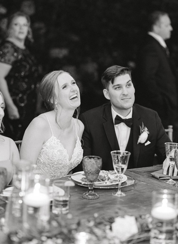Candid laughing photo of bride and groom during speeches.