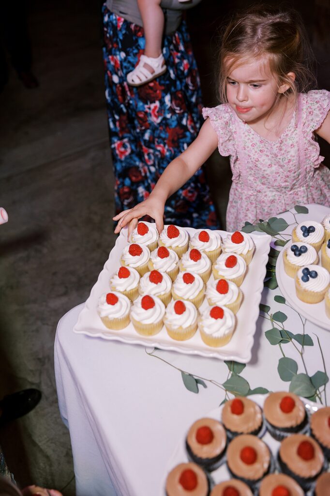 Child grabbing cupcake at wedding.
