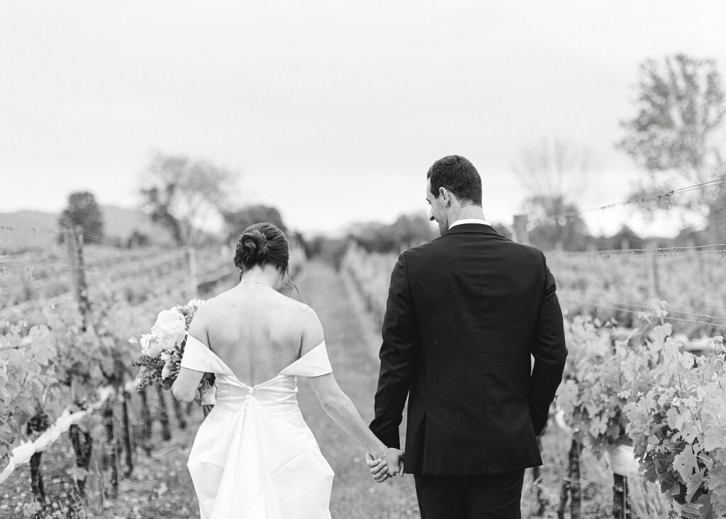 Bride and groom walking away through vines.