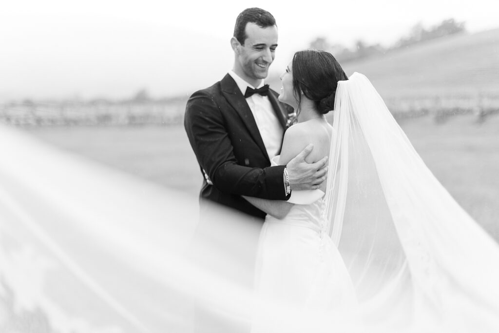 Wedding portrait with veil swooping in front of the camera.
