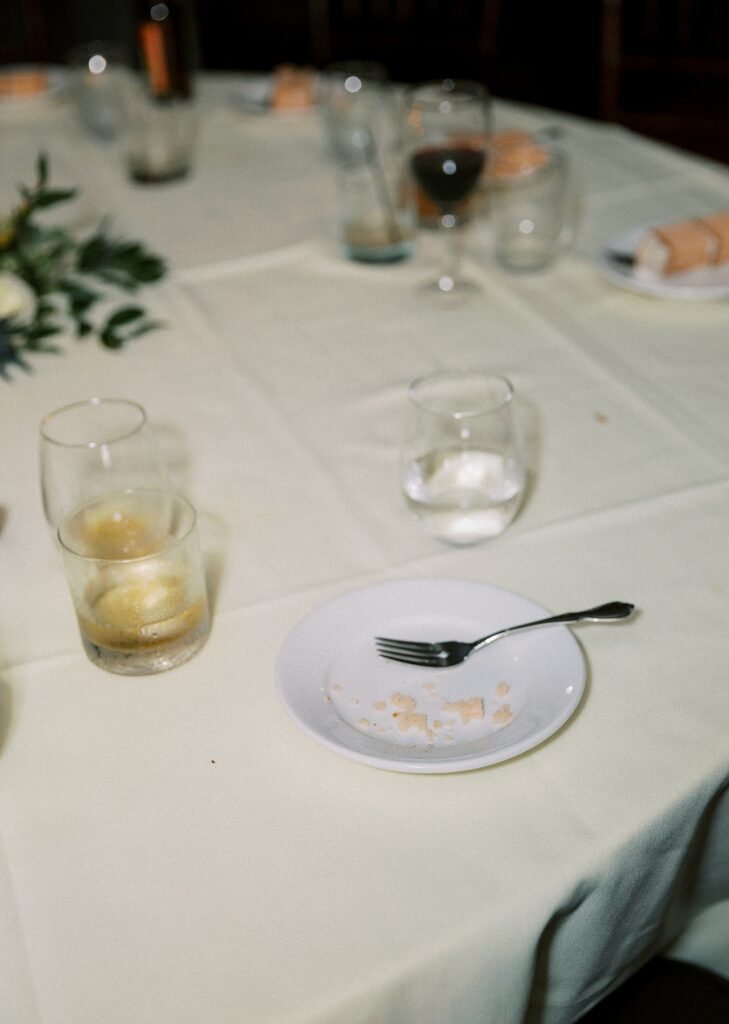 Empty cake plate and empty wine glass at wedding reception.