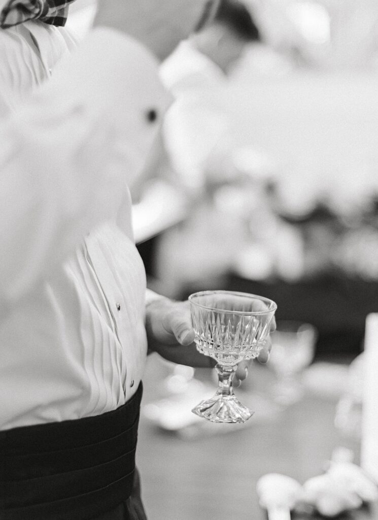 Black and white detail shot of man holding crystal glass.