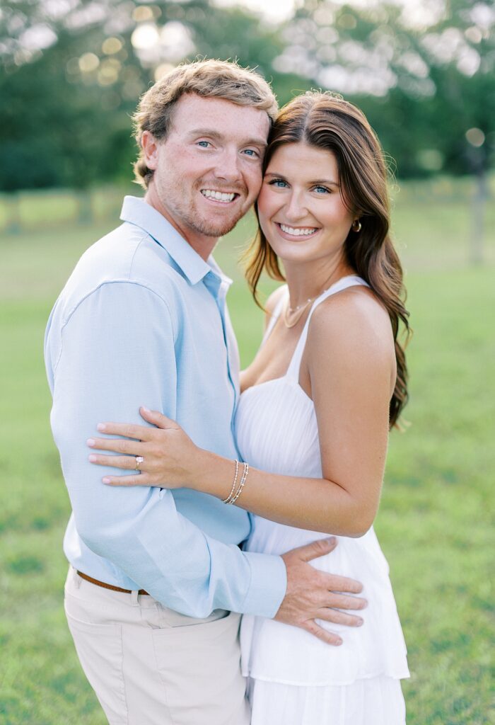 Newly engaged couple smiling at the camera.