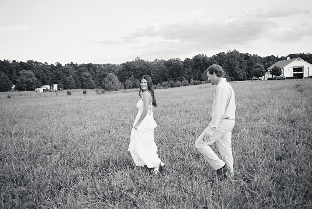 Woman leading her fiancé into field for engagement session in Richmond, VA.