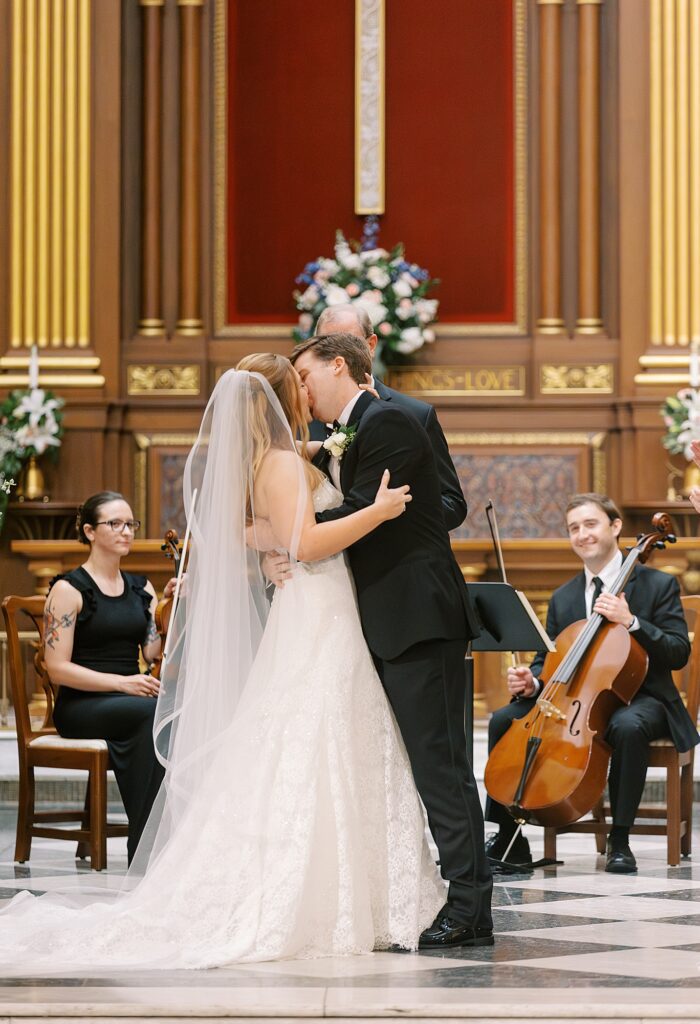 Bride and groom share a first kiss in church.